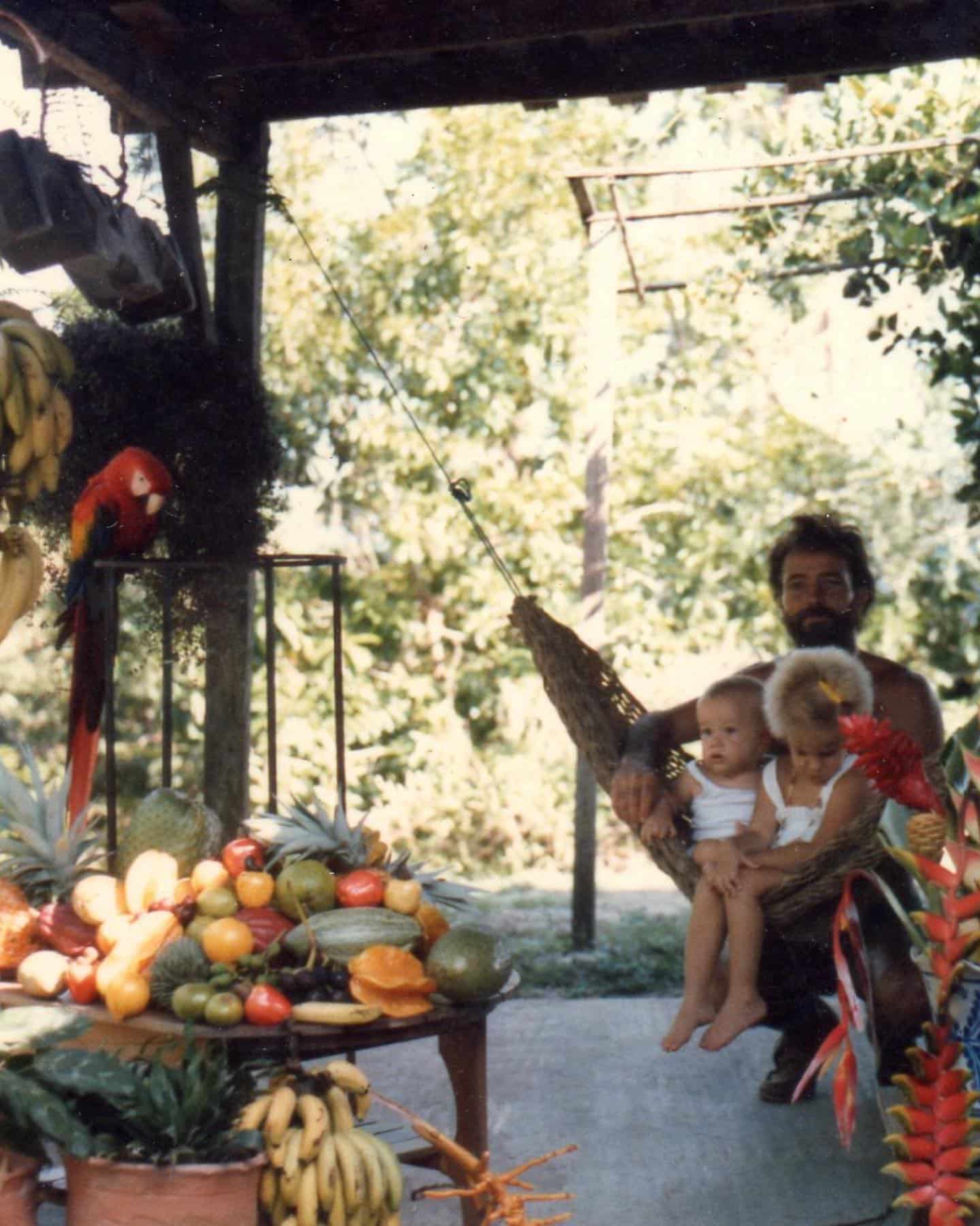 Peter Aspinall with Alanna and Clyde Aspinall beside tropical fruit and a scarlet macaw at Tiskita in 1985
